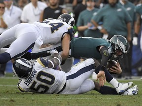 Philadelphia Eagles quarterback Carson Wentz, right, is tackled by Los Angeles Rams linebacker Samson Ebukam (50) and inside linebacker Bryce Hager during the second half of an NFL football game Sunday, Dec. 10, 2017, in Los Angeles.
