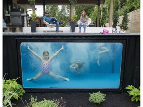 Paul Rathnam and his wife, Denise watch their three daughters, Savana, Sydney and Summer play in a Modpool, a shipping container converted into a pool/hot tub, in their backyard.