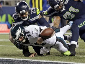 Philadelphia Eagles quarterback Carson Wentz fumbles the ball near the goal line and into the end zone as Seattle Seahawks' Earl Thomas (29) and Sheldon Richardson (91) move in during the second half of an NFL football game Sunday, in Seattle.
