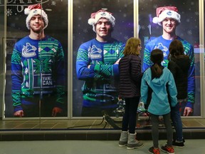 Fans check out the Christmas photos of Brandon Sutter, Bo Horvat and Henrik Sedin  before the Canucks game against the Dallas Stars at Rogers Arena Dec. 3, 2015.