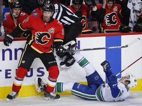 Brock Boeser of the Vancouver Canucks is knocked to the ice by Calgary Flames' Troy Brouwer during Saturday's NHL action in Calgary. Boeser scored his 15th goal of the season but the Canucks lost 4-2.