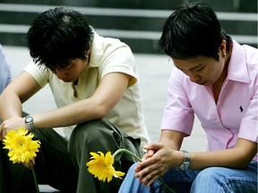 Mourners hold yellow flowers as they bow their heads during a vigil in support of Australian drug trafficker Nguyen Tuong Van in Sydney, Australia. Nguyen was hanged in Singapore in 2005.
