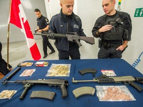 VPD Const. Jason Doucette holds an AR-15 in Vancouver as police unveil guns, ammunition and other items seized during a big gang bust, which included explosives, at a Langley property.