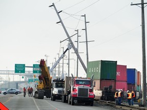 Crews work to lift a pole that was struck when a train derailed Sunday at the entrance to Deltaport in Delta.