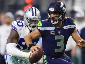 Russell Wilson of the Seahawks runs away from DeMarcus Lawrence of the Cowboys in the second half at AT&T Stadium on December 24, 2017 in Arlington, Texas.  (Photo by Ronald Martinez/Getty Images) ORG XMIT: 700070833