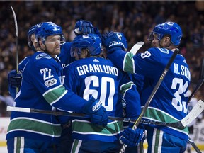 The Vancouver Canucks, including Daniel Sedin, left, and and Henrik Sedin, right, celebrate Markus Granlund's second goal against the San Jose Sharks during Friday's game at Rogers Arena.