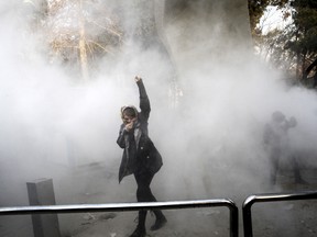 A university student attends a protest inside Tehran University while a smoke grenade is thrown by anti-riot Iranian police on Dec. 30, 2017.
