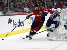 Washington Capitals center Nicklas Backstrom (19), from Sweden, skates withe the puck as Vancouver Canucks center Nic Dowd (17) defends during the first period of an NHL hockey game Tuesday, Jan. 9, 2018, in Washington.