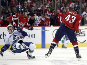 Vancouver Canuck Jake Virtanen falls to the ice after a hit by the Capitals' Tom Wilson.