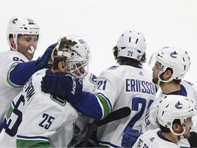 Vancouver Canucks goalie Jacob Markstrom (25) is surrounded and congratulated by teammates after the team's 3-2 overtime win in an NHL hockey game against the Minnesota Wild, Sunday, Jan. 14, 2018, in St. Paul, Minn.