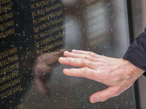 A person touches the name of Const. John Davidson on a police memorial at the Middle Engine Lane Police Station in Wallsand, U.K., in an undated police handout photo. Davidson's name has been added to a memorial for fallen officers in the U.K., after he was killed in November 2017 responding to reports of a stolen vehicle.