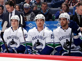 Bo Horvat, Daniel Sedin and Brandon Sutter of the Vancouver Canucks look on from the bench prior to puck drop against the Winnipeg Jets at the Bell MTS Place on January 21, 2018 in Winnipeg, Manitoba, Canada.