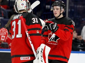 Drake Batherson of Canada gets congratulations from Carter Hart after scoring his second goal of the game on Jan. 2, 2018