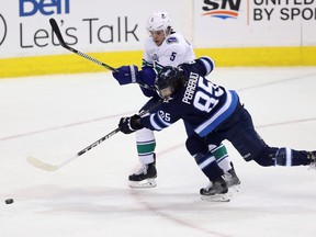 Winnipeg Jets' Mathieu Perreault (85) fires a shot in front of Vancouver Canucks' Derrick Pouliot (5) during first period NHL hockey action in Winnipeg, Sunday, January 21, 2018.