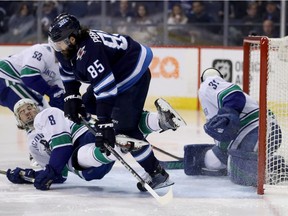Winnipeg Jets' Mathieu Perreault (85) hits Vancouver Canucks' Christopher Tanev (8) in front of goalie Anders Nilsson (31) during second period NHL hockey action in Winnipeg, Sunday, January 21, 2018.