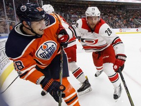 Carolina Hurricanes' Elias Lindholm (28) and Edmonton Oilers' Anton Slepyshev (58) battle for the puck during second period NHL action in Edmonton, Alta., on Tuesday October 17, 2017.