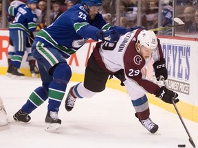 Vancouver Canucks defenceman Alexander Edler checks Colorado Avalanche centre Nathan MacKinnon during an NHL game on Jan. 30, 2018