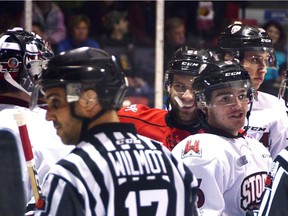 The Attack's Jonah Gadjovich smirks at Storm goalie Nico Daws after a close call in the Guelph crease while Top Prospect Ryan Merkley chats with the officials during the first period of Owen Sound's 2-1 win at the Harry Lumley Bayshore Community Centre.