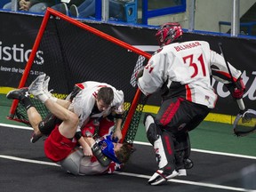 Vancouver Stealth goalie Tye Belanger grabs the net as Cliff Smith of the Stealth and the Toronto Rock's Brodie Merrill topple into it during a fight Saturday.