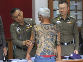 Japanese gang member Shigeharu Shirai displays his tattoos at a police station during a press conference in Lopburi, central Thailand, Thursday, Jan. 11, 2018.