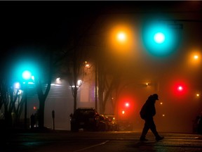 A man walks across a street as thick fog fills the air in the Downtown Eastside of Vancouver, B.C., late Wednesday December 6, 2017.