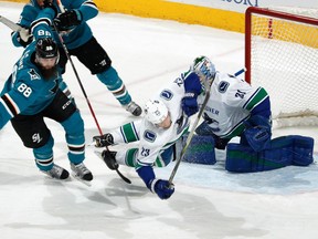 Alex Edler takes a tumble while defending Brent Burns of the Sharks.