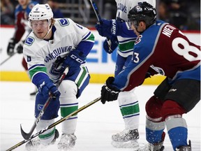 Brock Boeser, left, shoots the puck past the Avalanche's Matt Nieto in the second period.