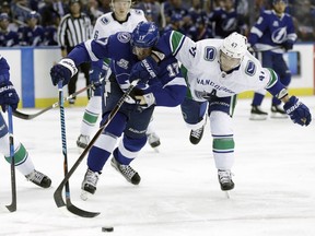 Tampa Bay Lightning left wing Alex Killorn (17) and Vancouver Canucks left wing Sven Baertschi (47) battle for the puck during the second period of an NHL hockey game Thursday, Feb. 8, 2018, in Tampa, Fla.