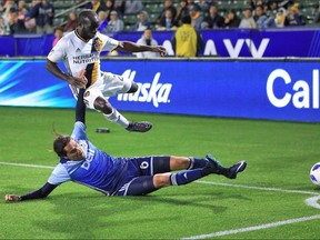 Efrain Juárez of the Whitecaps slides under L.A.'s Emmanuel Boateng during Saturday night's game at StubHub Center in Carson, Calif.