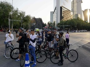 Cyclists use their mobile phones during a powerful earthquake in Mexico City on Friday, Feb. 16, 2018.