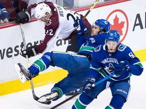 Michael Del Zotto, centre, is tripped up by the Avalanche's Colin Wilson, left, behind Troy Stecher.