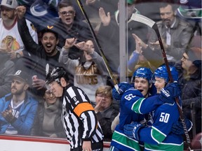Vancouver Canucks' Bo Horvat, centre, and Brendan Gaunce, right, celebrate Gaunce's goal against the Chicago Blackhawks as referee Dave Jackson looks on during the second period of an NHL hockey game in Vancouver, B.C., on Thursday February 1, 2018.