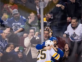 Fans react as Vancouver Canucks' Darren Archibald, back, and Boston Bruins' Brandon Carlo fight during the second period of an NHL hockey game in Vancouver, B.C., on Saturday February 17, 2018.