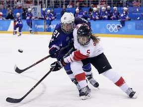 Lauriane Rougeau of Canada, right, and Hilary Knight of the United States battle for the puck during the Olympic gold-medal final earlier this week in Gangneung, South Korea. The U.S. struck gold with a 3-2 victory in a shootout.
