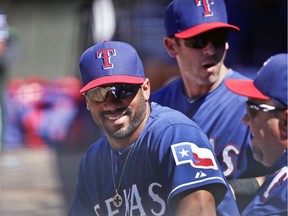 This March 28, 2015 file photo shows Seattle Seahawks quarterback Russell Wilson talking with fellow Texas Rangers in the dugout during a spring training baseball game.  between the Texas Rangers  Wilson has been traded from the Texas Rangers to the New York Yankees and will attend spring training on Monday.