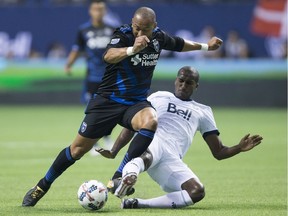 Whitecaps' Aly Ghazal slides to take the ball away from San Jose Earthquakes' Victor Bernardez during an MLS playoff game in Vancouver on Oct. 25, 2017.