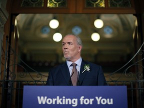 Premier John Horgan answers questions from the media Tuesday after the throne speech in the legislative assembly in Victoria.