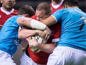 Canada's Nick Blevins, centre, is tackled by Uruguay's Felipe Berchesi, left, and Franco Lamanna during the second half of a Rugby World Cup qualifier match in Vancouver, B.C., on Saturday January 27, 2018.