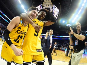 K.J. Maura #11 and teammate Jourdan Grant #5 of the UMBC Retrievers celebrate their 74-54 victory over the Virginia Cavaliers during the first round of the 2018 NCAA Men's Basketball Tournament at Spectrum Center on March 16, 2018 in Charlotte, North Carolina.