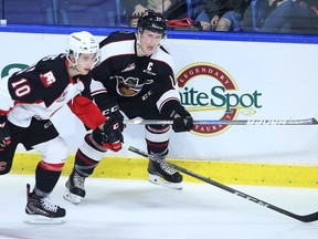 Tyler Benson of the Vancouver Giants plays the puck against Josh Curtis of the Prince George Cougars (left) during their WHL game at the Langley Events Centre last fall.