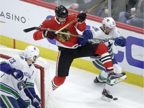 Chicago Blackhawks' Artem Anisimov (15) and Vancouver Canucks' Alex Biega (55) battle for a loose puck as Alexander Edler (23) watches during the second period of an NHL hockey game Thursday, March 22, 2018, in Chicago.