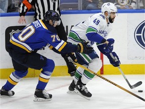 St. Louis Blues' Oskar Sundqvist (70), of Sweden, reaches for the puck with Vancouver Canucks' Darren Archibald (49) during the second period of an NHL hockey game, Friday, March 23, 2018, in St. Louis.