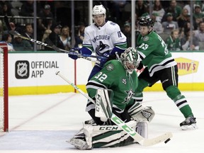 Kari Lehtonen deflects a shot from the Canucks as Jake Virtanen and Marc Methot battle beside the net.