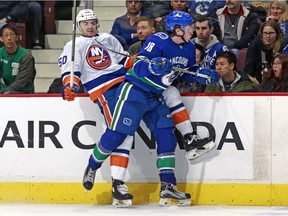 Jake Virtanen checks Adam Pelech of the Islanders into the boards on Monday.