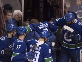 Members of the Vancouver Canucks look on as teammate Brock Boeser is taken off the ice following a hit from New York Islanders winger Cal Clutterbuck during third-period NHL action in Vancouver on Monday.