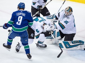 San Jose Sharks' Marc-Edouard Vlasic, right, is struck by the puck as Vancouver Canucks' Brendan Leipsic attempts to redirect it during the second period of an NHL hockey game in Vancouver, B.C., on Saturday March 17, 2018.
