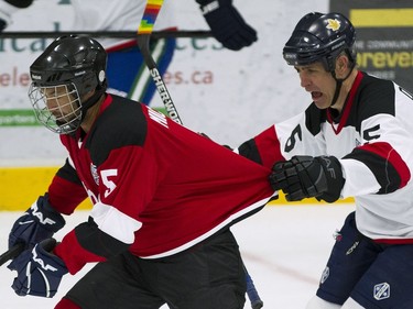 Team Rockers Victor Micallef is grabbed by Team NHL and Olympians Brad Dalgarno during the first period of the 15th annual Juno Cup hockey game at the Bill Copeland Sports Centre in Burnaby.