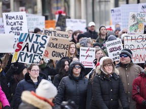 People hold up signs during a 'March of Our Lives' rally to show solidarity with the U.S. gun control movement in Montreal, Saturday, March 24, 2018.