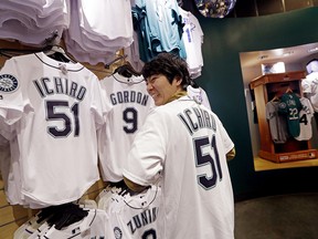 Yu Okubo, visiting from Tokyo, smiles as he tries on a Seattle Mariners' Ichiro Suzuki jersey before buying the $138 shirt at the baseball team's store Tuesday, March 6, 2018, in Seattle.  The Seattle Mariners are bringing back Ichiro Suzuki.