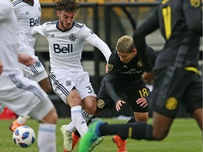 Vancouver Whitecaps midfielder Russell Teibert (31) pushes Columbus Crew midfielder Cristian Martinez (18) during an MLS game in Columbus, Ohio, on March 31.